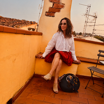 Lucy seated on rooftop terrace with black LUCY bag at her feet