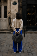 woman on cobblestone street holding black LUCY bag as tote
