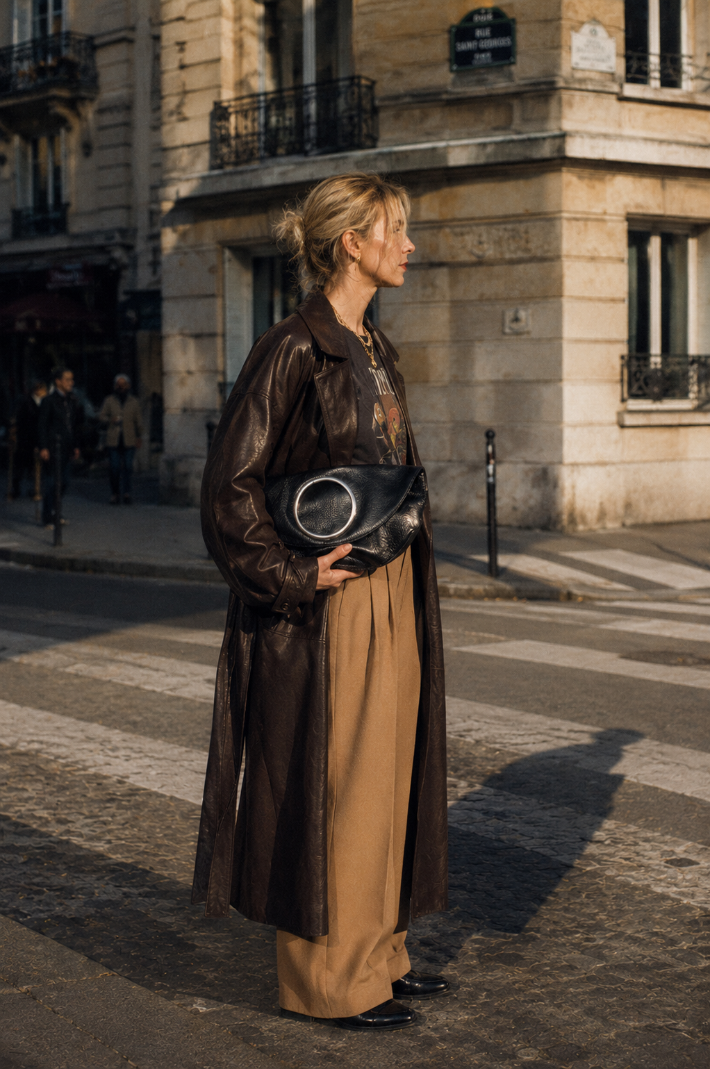 woman in long leather coat carrying black LUCY clutch, Parisian street